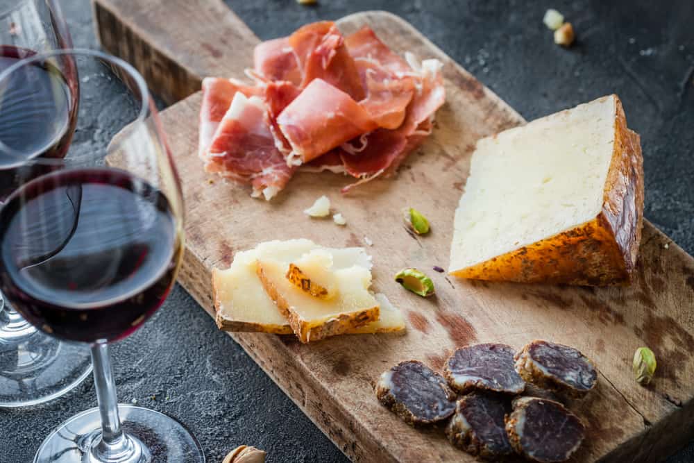 Käseplatte mit Serrano-Schinken, Wein und getrockneter Salami